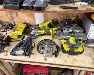 Assorted power tools including Ryobi reciprocating saws, angle grinders, and batteries, and other workshop equipment.