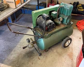 Vintage Craftsman green portable air compressor with a horizontal tank, electric motor, and integrated handle and wheels.