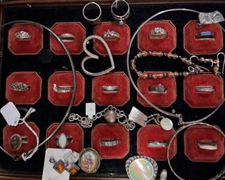 Assorted sterling silver and costume jewelry collection, including rings, bracelets, necklaces, and pendants, displayed in a red velvet-lined tray.