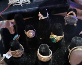 Assortment of vintage rings, including sterling silver, turquoise, and gemstone styles, displayed on a black velvet stand.