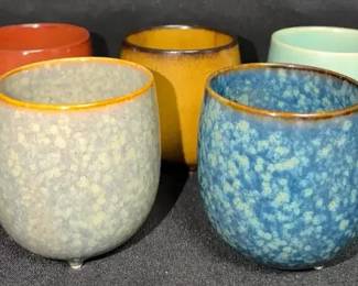 five small, round, footed ceramic tea cups
