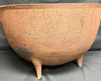antique castiron cauldron featuring three legs and side loop handles.