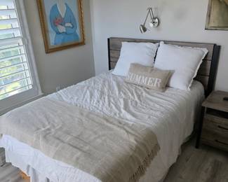 Gray plank headboard bed with fringed throw below woman-in-blue print