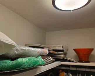 Bubble-wrapped framed art, pillows and orange art glass vase in closet