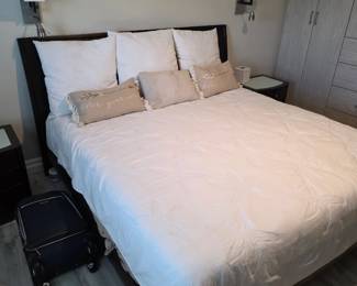 Bed with dark headboard, white bedding, euro shams and lumbar pillows