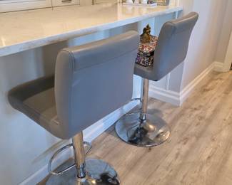 Pair of gray faux leather swivel bar stools with chrome pedestal bases