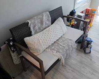 Resin wicker loveseat with white cushion, popcorn pillow and gray throws