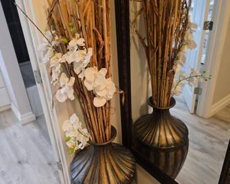 Ribbed bronze-tone floor vase with faux orchids and black floor mirror