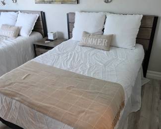 Pair of beds with gray plank headboards, white quilts and plaid throw