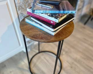 Round wood-top accent table on black metal ring base with cookbooks
