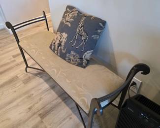 Wrought iron scroll-arm bench with cream cushion and safari toile pillow