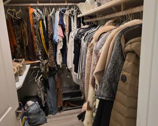 Closet of women's clothing with faux fur coats, puffer jacket and handbags