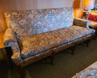 vintage sofa features a charming brown and blue floral tapestry upholstery paired with elegantly carved cabriole legs