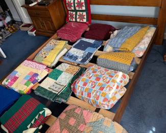 Large collection of handmade quilts and coverlets laid out on a bed