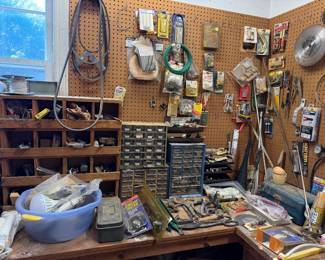 Workshop corner with pegboard hardware, parts organizer cabinets, a wooden sorting rack, saw blades and hand tools