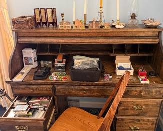Oak roll top desk with matching swivel chair, topped with candlesticks, an oil lamp and miniatures