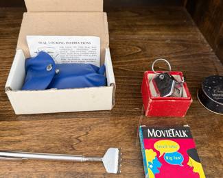 Boxed embossing seal with instructions, a telescoping back scratcher and a MovieTalk card game