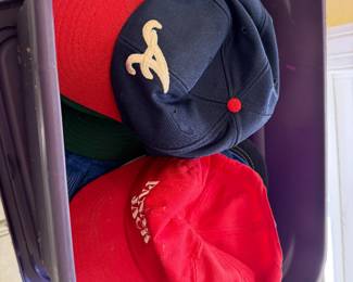 Bin of baseball caps including an Atlanta Braves cap