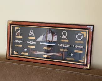 Framed nautical knot board with labeled sailor's knots and a model ship
