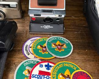 Polaroid SX-70 Land Camera Alpha 1, a Nikon compact camera and vintage Scout patches