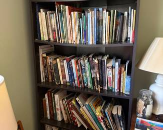 Dark wood corner bookcase filled with books and a carved praying hands sculpture