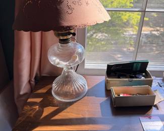 Glass font table lamp with a pink cut out shade and boxes of sewing notions