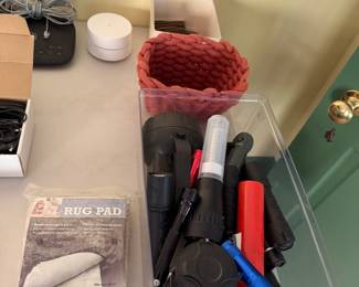 Bin of flashlights and hand tools with a packaged Mohawk rug pad