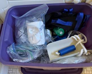 Bin of home medical supplies including a nebulizer, oxygen regulator, tubing and a transfer board