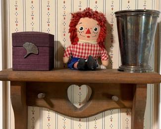 Raggedy Ann doll, fabric covered box and a silverplate julep cup on a heart cutout wall shelf