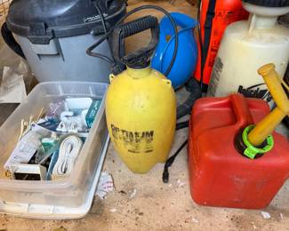 Shop vacuum, garden sprayers, a gas can and a bin of plumbing and electrical supplies