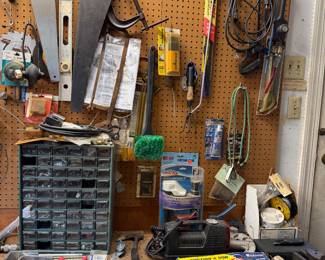 Workbench and pegboard with hand saws, levels, clamps, pliers and a parts organizer cabinet