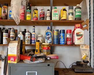 Garage shelving with paints, lubricants, weed killer and cleaning sprays over a filing cabinet