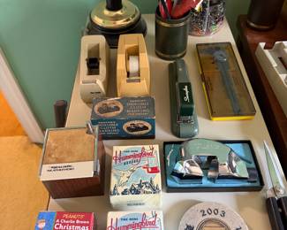 Boxed hummingbird feeders, a Peanuts Christmas book and tree kit, weather radio, stapler and desk accessories