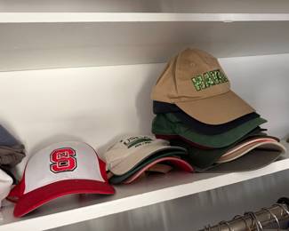 Shelf of baseball caps including NC State, USDA and Hawaii