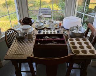 Table of bakeware and kitchenware with muffin tins, a silverware chest and a cake carrier