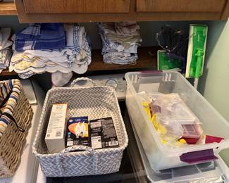 Laundry area with folded kitchen towels, boxed LED bulbs, storage bins and a Swiffer mop