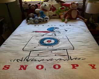Four poster bed with a Snoopy blanket and a group of plush animals
