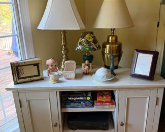 White console cabinet with two brass table lamps, figurines and children's science kits