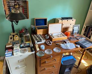 Office corner with a wood desk, tole lamp, filing cabinet and wood collector's display cases