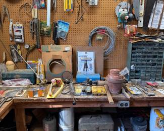 Second workbench and pegboard with saws, levels, wire, hand tools, electric motors and a toolbox