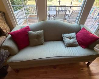 Camelback sofa in sage green upholstery with throw pillows