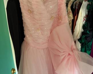 Pink beaded formal gown with ruched bodice and bow, in a closet of evening wear