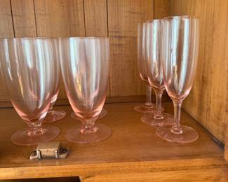 Pink glass goblets and champagne flutes with blue banded china below