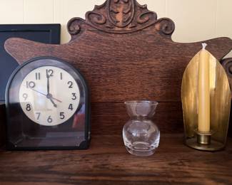 Arched mantel clock, glass bud vase and brass candle sconce on a carved oak sideboard