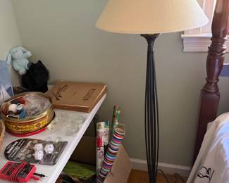 Wrought iron floor lamp with cream shade, sewing tin and rolls of gift wrap