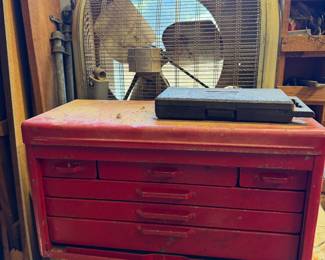 Red machinist's tool chest with drawers, a vintage box fan and a wall clock