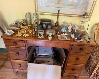 Oak kneehole desk topped with brass candlesticks, pottery, glass oil lamp and figurines