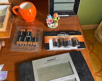SkyScan atomic clock, AcuRite weather station, orange mug, gnome figurine and packaged batteries