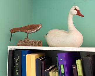 Carved shorebird decoy on a stand and a white carved swan decoy
