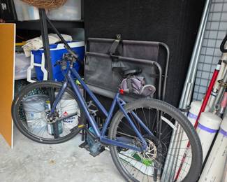 Blue bicycle with disc brakes, gray folding cots and blue cooler